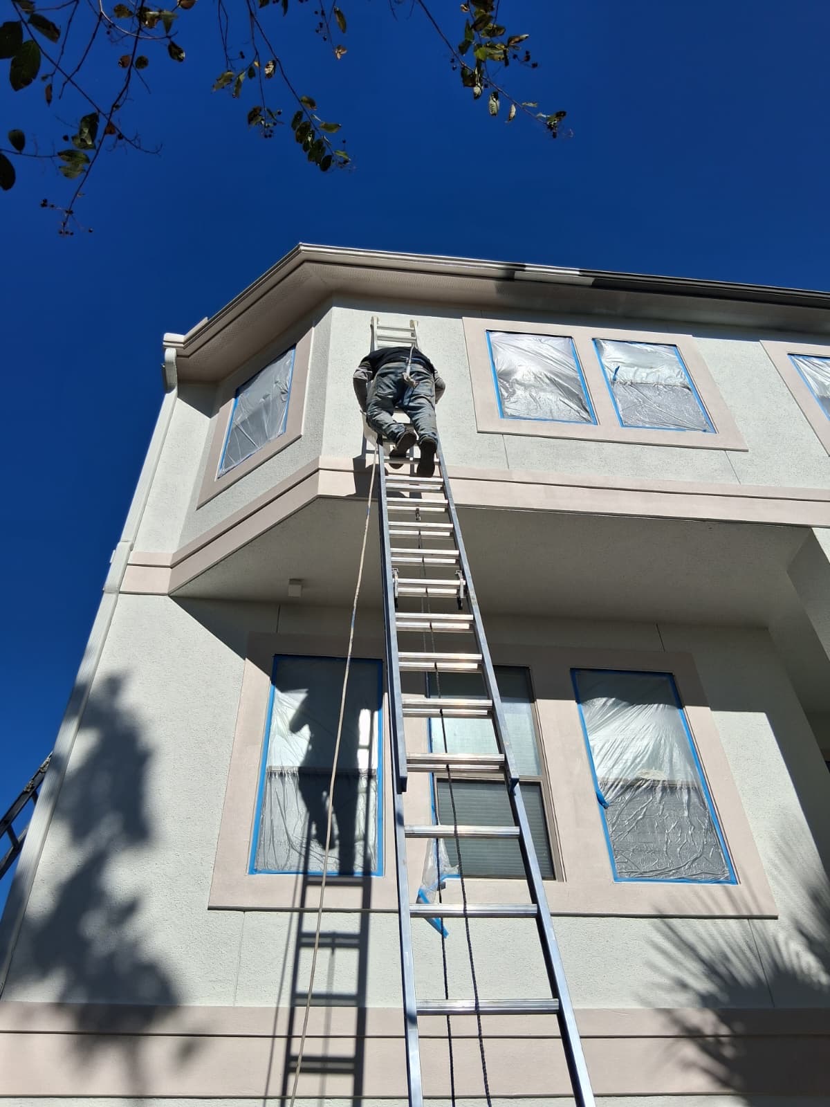 Exterior painting in progress with taped windows by Dominguez Painting